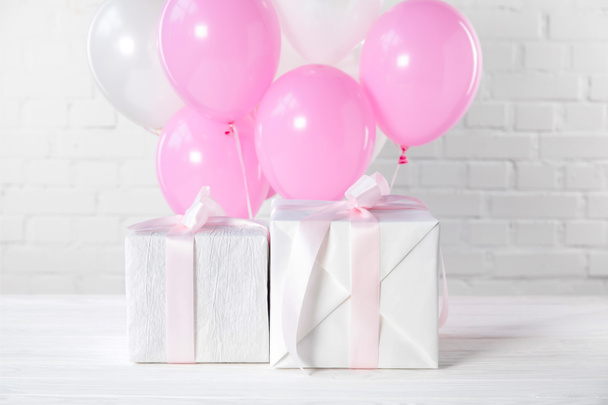 Κουτιά δώρων και διακοσμητικά μπαλόνια σε φόντο λευκό τούβλο τοίχο - Φωτογραφία, εικόνα
