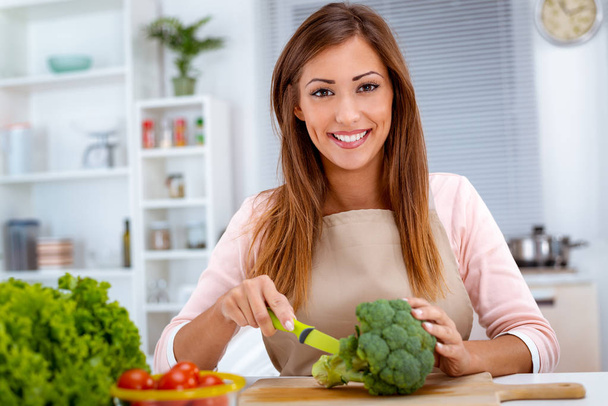junge Frau bereitet vegetarisches Essen auf Küchentisch zu - Foto, Bild