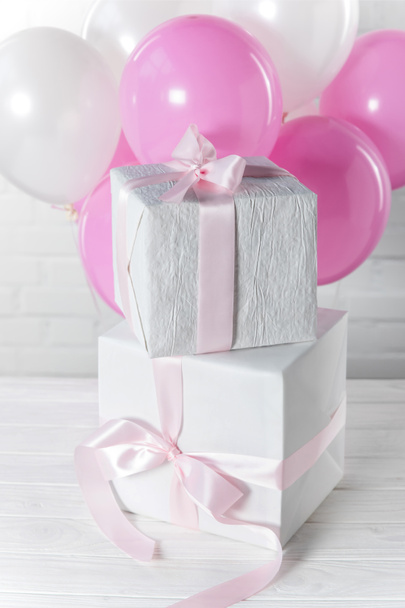 Упакованные коробки подарков и яркие воздушные шары на фоне стены из белого кирпича
 - Фото, изображение