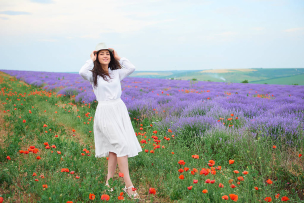 mladá žena je v poli levandule, krásné letní krajina s červenými květy máku - Fotografie, Obrázek
