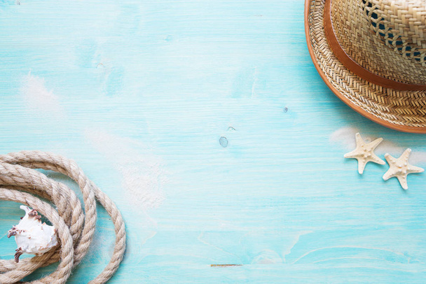 Rough hemp rope, shell, starfishes, white sea sand and straw hat are on the background of blue faded wooden deck. Marine concept - Photo, image