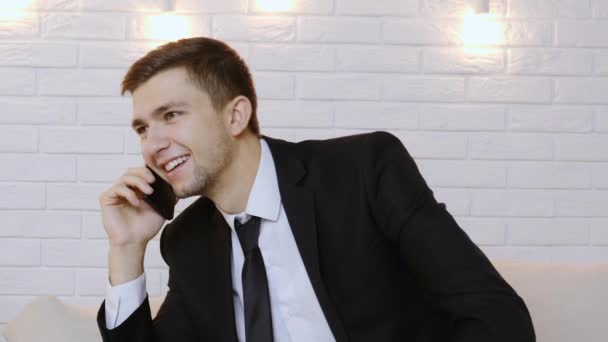 Muotokuva nuoresta miehestä mustassa puvussa puhumassa puhelimessa
 - Materiaali, video