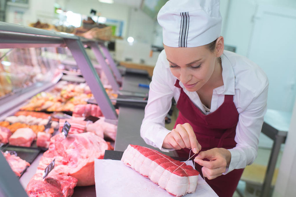female butcher tying joint of meat - Foto, Imagem
