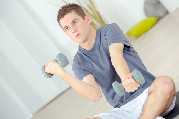 Young man working out with dumbbells - Fotó, kép