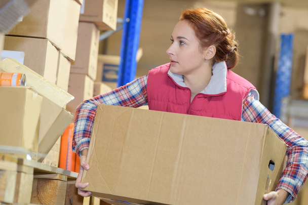 Женщина держит коробку на складе
 - Фото, изображение