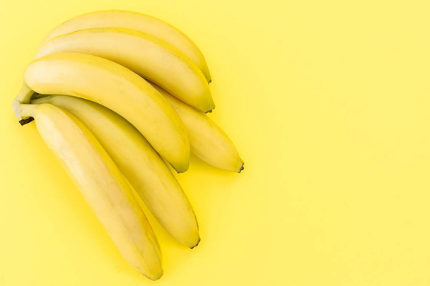 Fresh ripe bananas on a yellow background - Foto, afbeelding