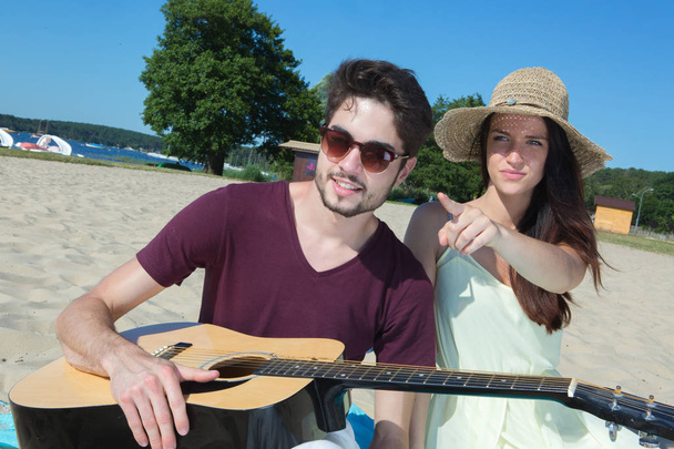 young man with his guitar and girlfriend on the beach - Photo, image