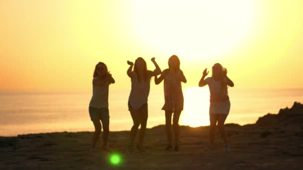 Letní žena skočí siluety na západ slunce nad pláží. Hravé holky si moře západ slunce - Záběry, video
