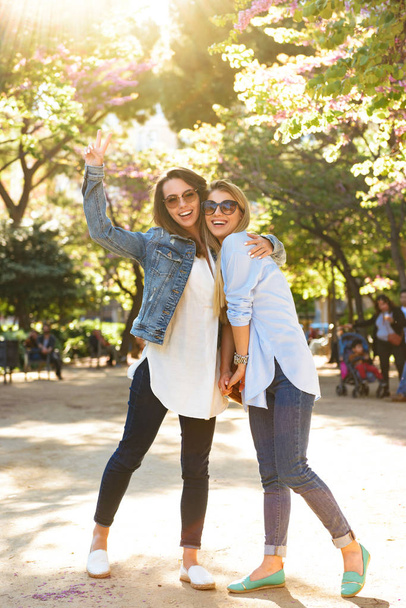 Image of two amazing happy women friends outdoors showing peace gesture looking camera. - Valokuva, kuva