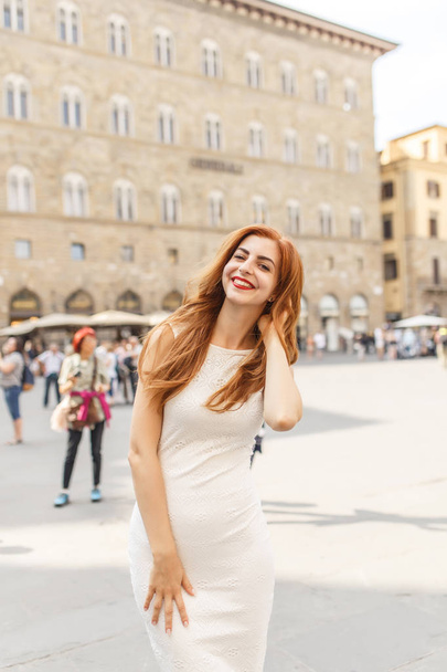 Attractive redhead woman in white dress posing on street of Florence - Φωτογραφία, εικόνα