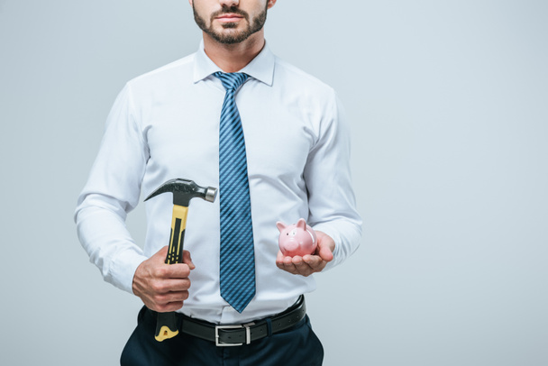 обрезанное изображение финансиста, стоящего с копилкой и молотком, изолированным на сером
 - Фото, изображение