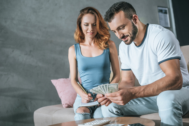 couple planning family budget and counting money in living room - Photo, Image