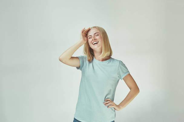 The happy freckled woman standing and smiling against gray background. - Foto, Bild