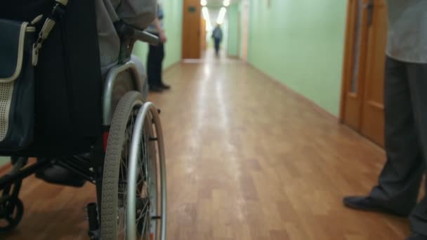 Disabled man on a wheelchair standing inside hospital or university, close up - Footage, Video