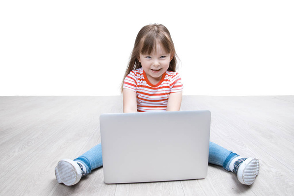 Little girl is sitting on floor with her laptop - Foto, Imagen
