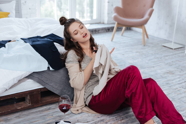 Woman wearing dark-red pajama trousers cutting sweater with scissors - Foto, Imagem