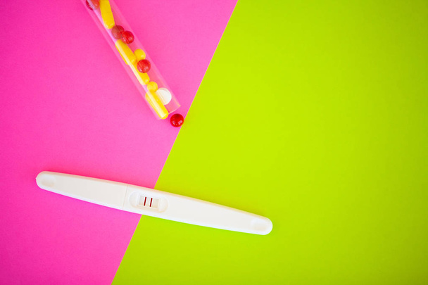 Test de grossesse. Le résultat est positif avec deux bandelettes et un préservatif avec contraceptif sur fond coloré, pilule contraceptive, relations sexuelles protégées, conception de soins de santé
 - Photo, image