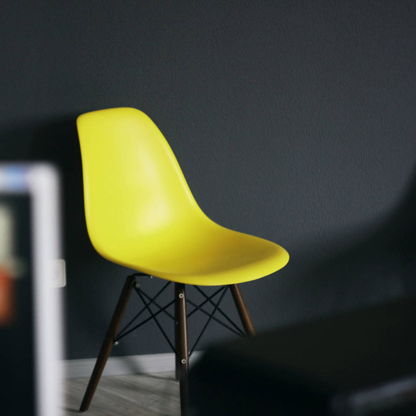 Yellow chair against black wall, details of modern office interior - Фото, изображение