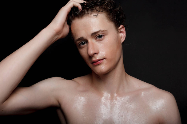 people, skincare and beauty concept - Wet young man with black hair on a black background. Portrait male with shaved chest . Men's skin care. Ripped muscular handsome man on black background - Valokuva, kuva
