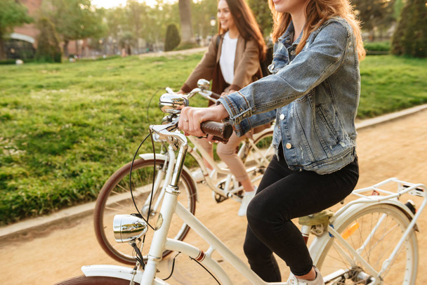屋外公園に自転車で 2 人の若い女性の友人の画像をトリミング. - 写真・画像