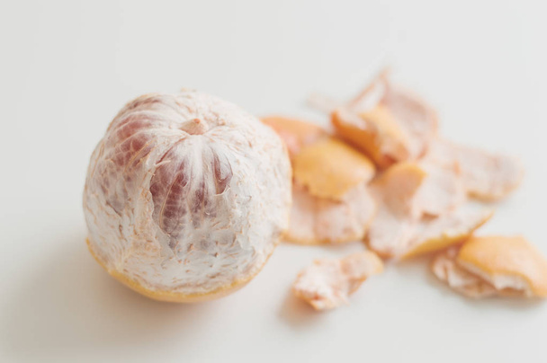 Whole grapefruit and its peel on white table. Minimal photo - Foto, afbeelding