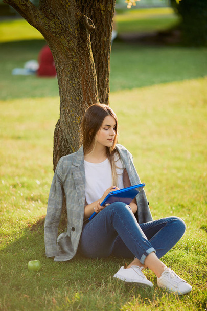 Pretty girl with her book in park background, sunset - Foto, Bild