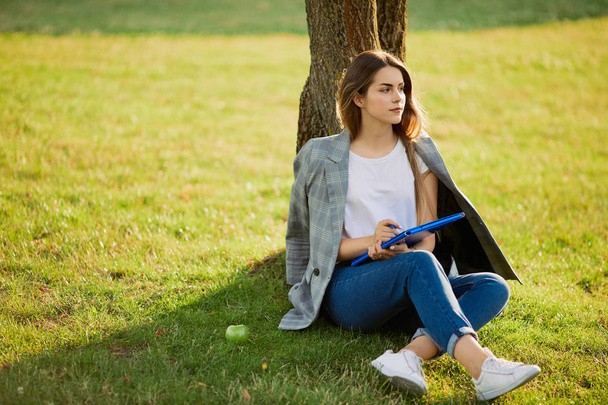 Pretty girl with her book in park background, sunset - Fotoğraf, Görsel