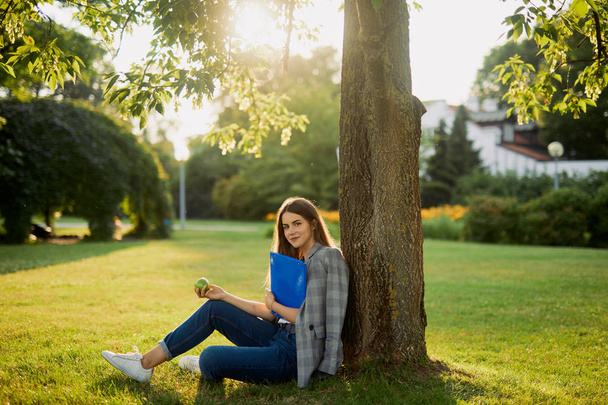 Pretty girl with her book in park background, sunset - Zdjęcie, obraz