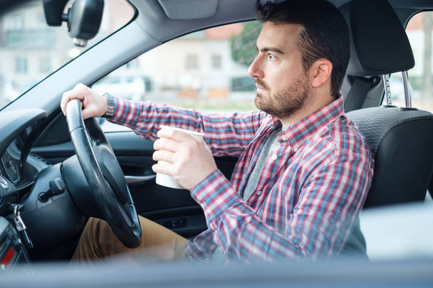 Portrait of man drinking coffee while driving car - Фото, зображення