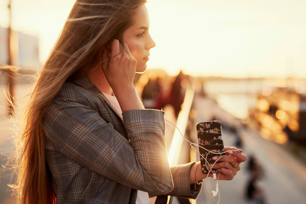 Mooi meisje praten op haar telefoon met zonsondergang achtergrond - Foto, afbeelding