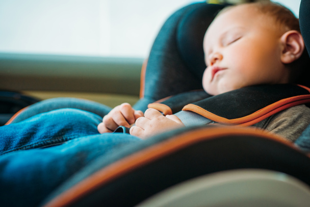 крупным планом портрет очаровательного малыша, спящего на детском сиденье в машине
 - Фото, изображение