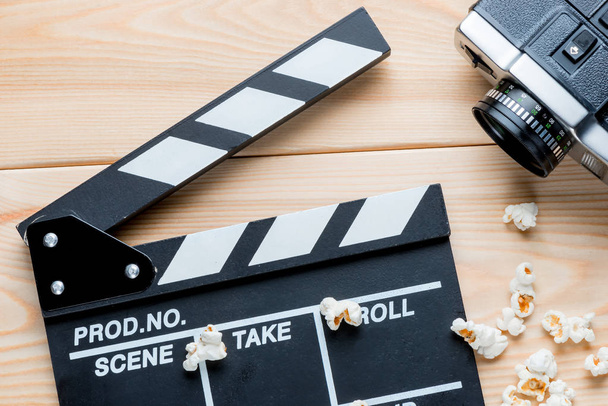 Open video klepel, retro video-camera en gezouten popcorn bovenaanzicht op houten planken - Foto, afbeelding