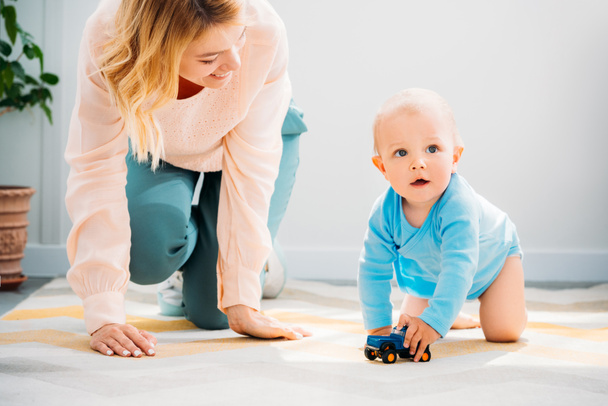 mother and child crawling together on carpet at home - Foto, imagen