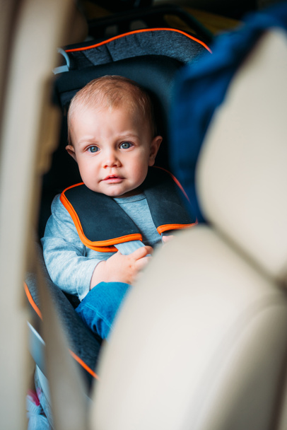 piccolo bambino seduto nel seggiolino di sicurezza in auto e guardando la fotocamera
 - Foto, immagini