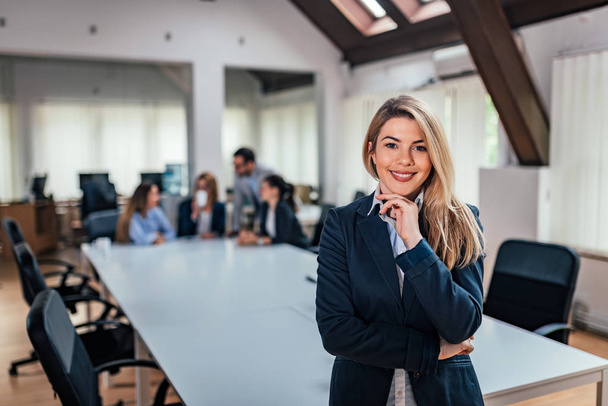 Portrait of a business woman with a team in meeting in background. - Photo, image