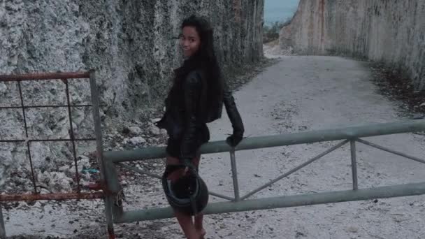 Beautiful happy woman motorcycle rider walking with helmet near amazing limestone cliffs. Girl getting over stile and gesturing come along follow me - video in slow motion - Footage, Video