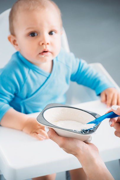 cropped shot of mother feeding child with porridge - 写真・画像