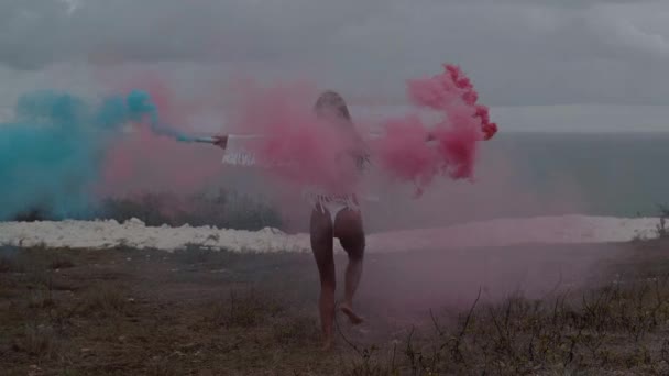 Színes füst futás-on a hegyi mező-óceán és a felhős ég háttér - videó, lassítva a gyönyörű lány hátulnézet - Felvétel, videó