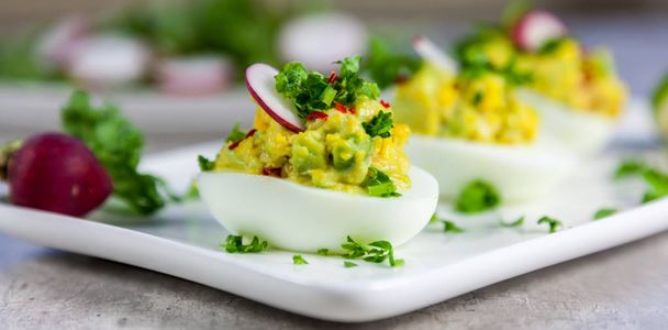 Gevulde eieren met avocado, peterselie, chili en radijs - gezond ontbijt - Foto, afbeelding