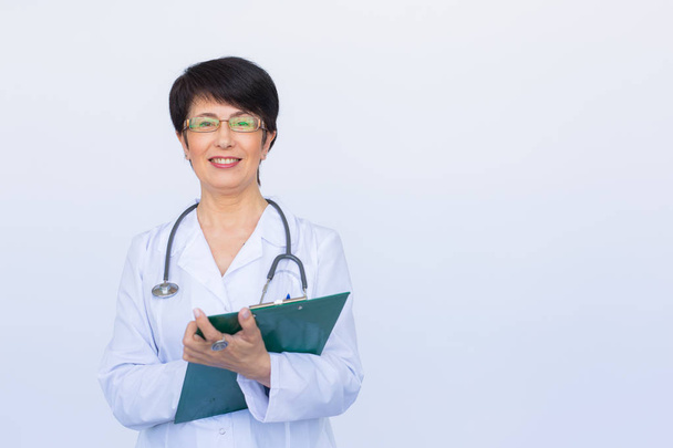 Portrait Of Female Doctor Writing On Clipboard Over a white background with copy space - Foto, Bild