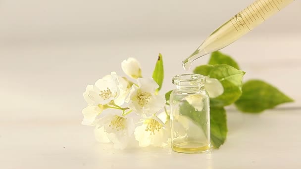 Essence of flowers on white background in beautiful glass jar - Footage, Video
