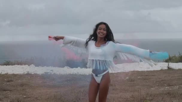 Gyönyörű lány, színes füst óceán és felhős ég háttér - videó, lassítva a hegyvidéki területen játszik - Felvétel, videó