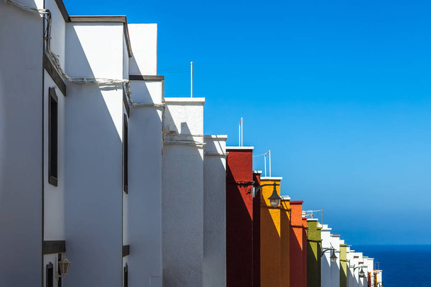 Multicolored houses on island tenerife, side view. Colorful facades of buildings lined up in row under blue tropical sun - 写真・画像
