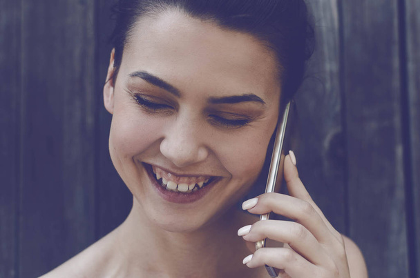 Young woman talking using smartphone and smiling with closed eyes. - Фото, изображение