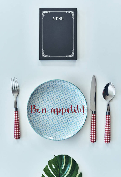 plano plano tiro de plato vacío, tenedor, cuchara, cuchillo y menú cerrado acostado en la mesa, buen apetito
 - Foto, Imagen