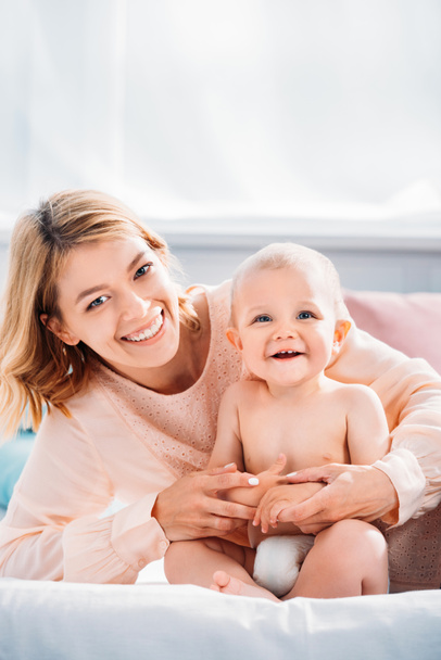 happy mother and child relaxing on bed at home and looking at camera - Fotoğraf, Görsel