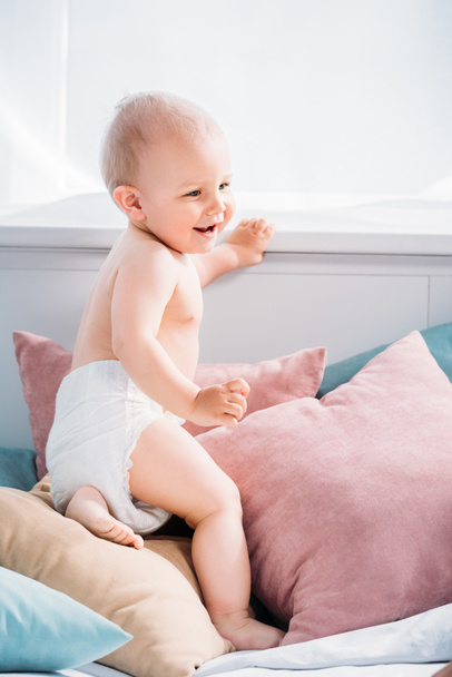 happy little baby on bed with lot of pillows - 写真・画像