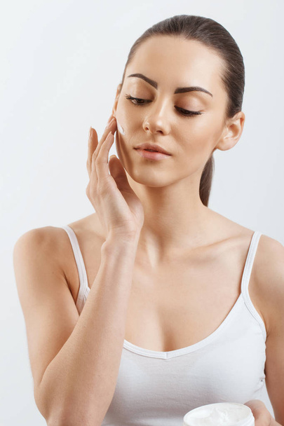 Young woman applying cream to her face. Skincare and cosmetics concept.Cosmetics. Woman face skin care. - Valokuva, kuva