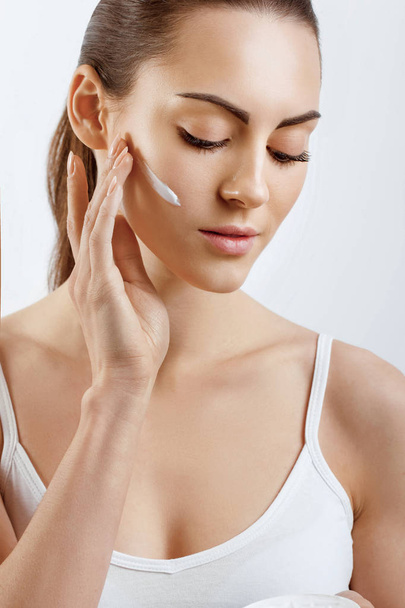 Young woman applying cream to her face. Skincare and cosmetics concept.Cosmetics. Woman face skin care. - Valokuva, kuva