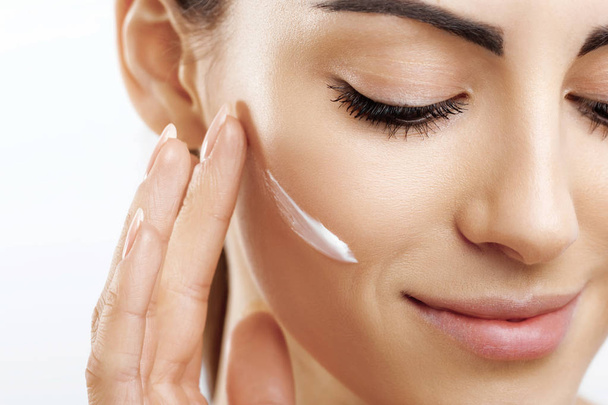 Closeup happy young woman applying cream to her face Skincare and cosmetics concept. Cosmetics. Woman face skin care.Natural makeup, touching face. - Valokuva, kuva